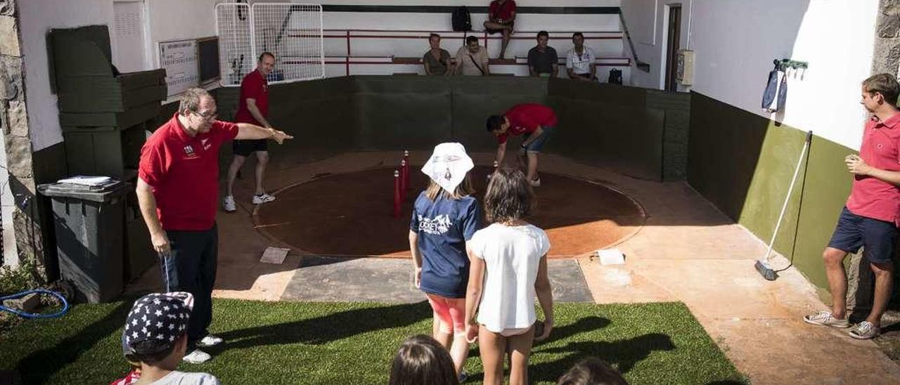 Valentín Estrada da indicaciones a varios niños, con Ángel Luis Menéndez y José Manuel Gueimonde al fonfo de la bolera.