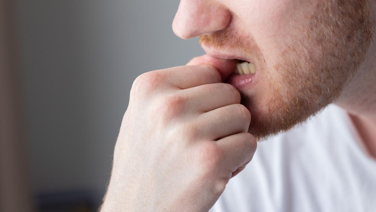 Un hombre se muerde las uñas.