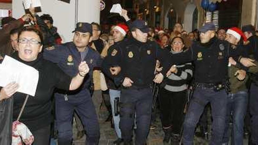 Policías nacionales conteniendo a los manifestantes que perseguían a un grupo de concejales.