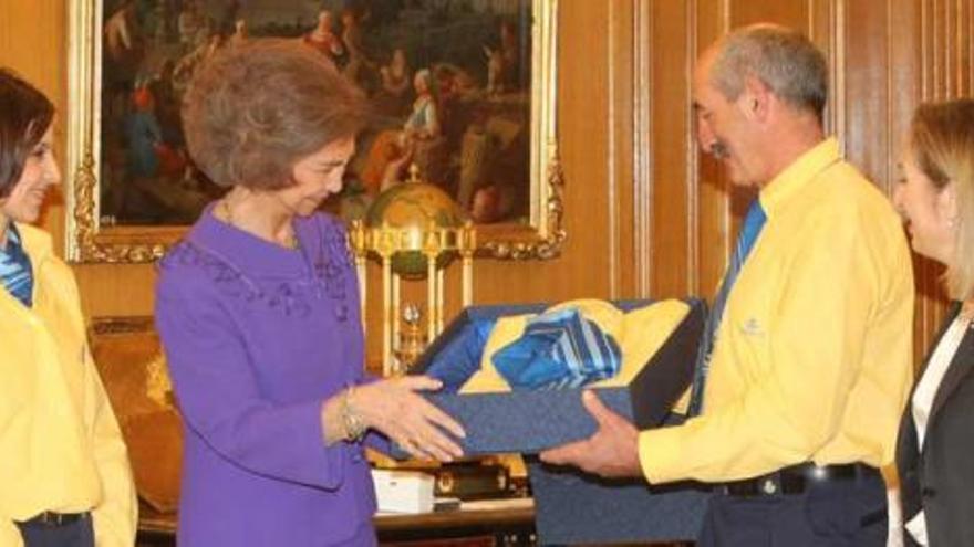 Ramón González, entregando la chaqueta de Correos a doña Sofía ayer en Madrid; a la derecha, Ana Pastor.