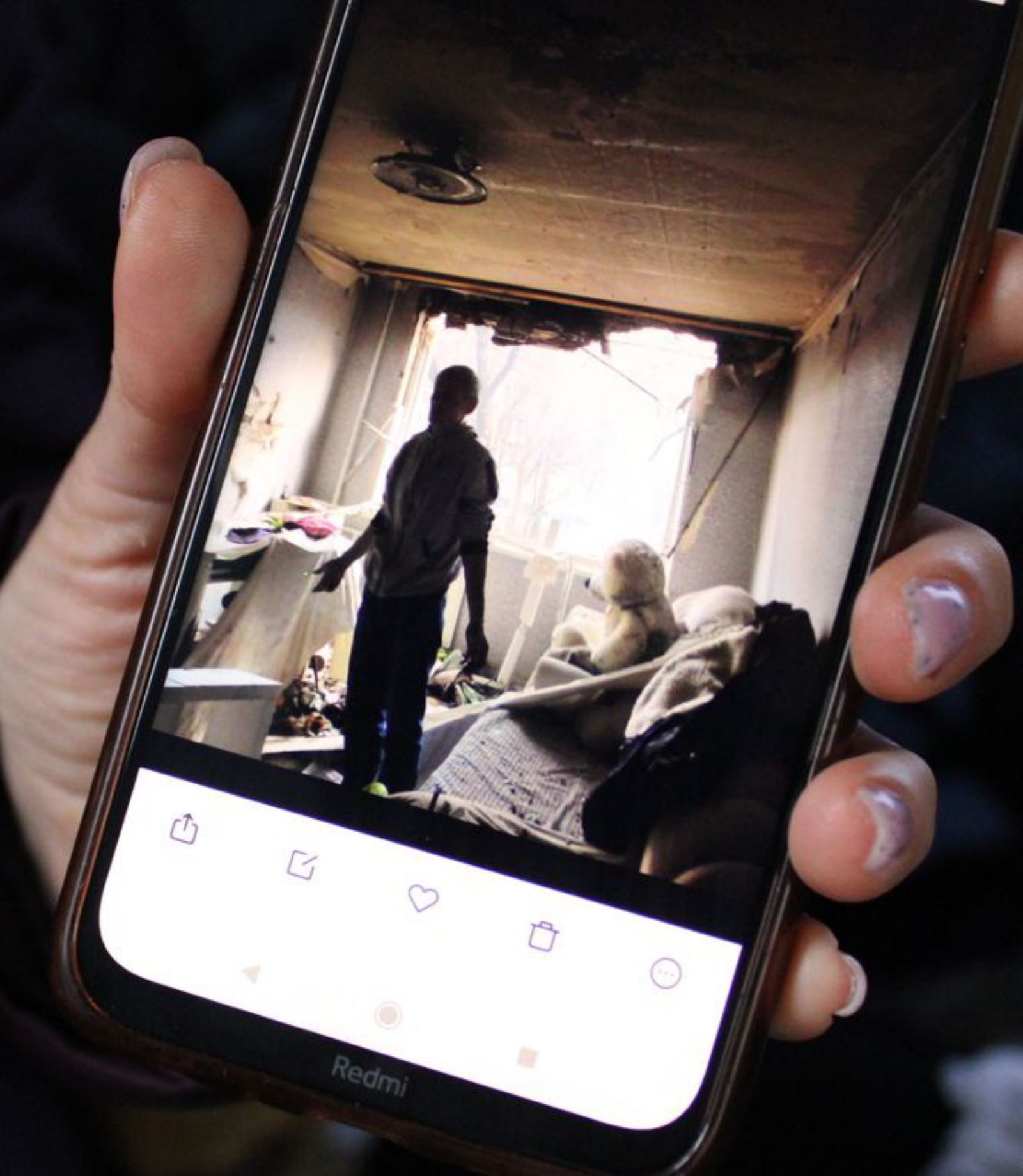 Shushanna muestra en su móvil cómo quedó su casa tras los bombardeos. Su hermano contempla la destrucción provocada por las tropas de Putin.