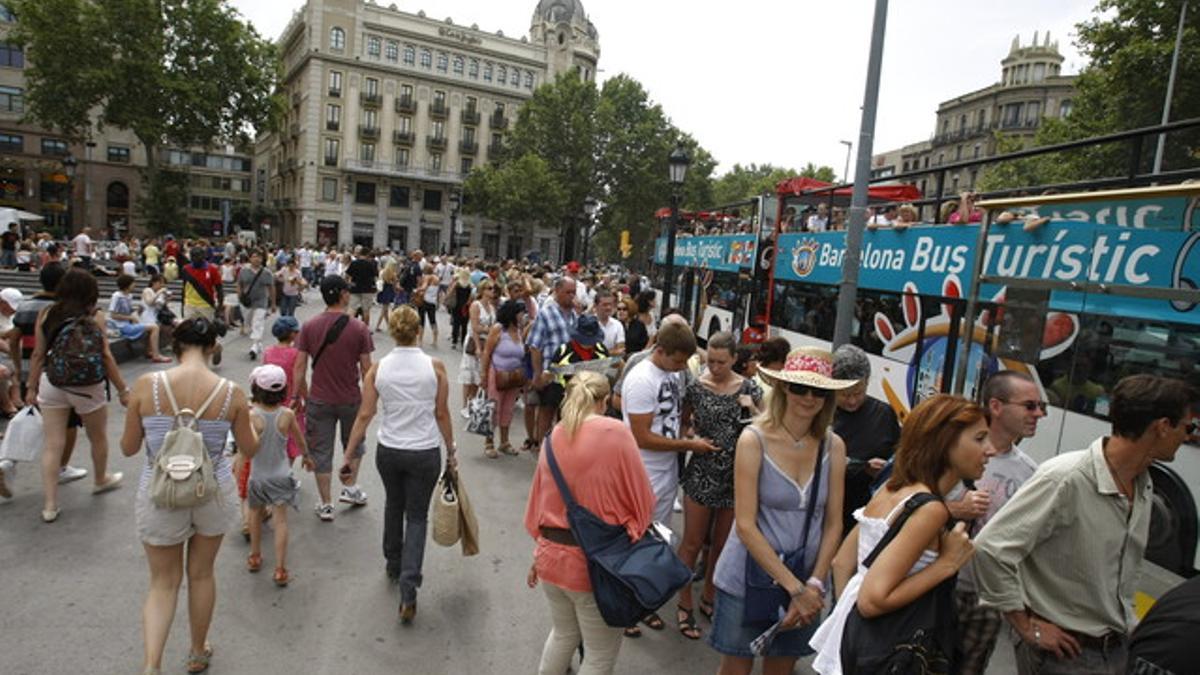 Grandes colas de visitantes para coger el Bus Turístic en plaza Catalunya.