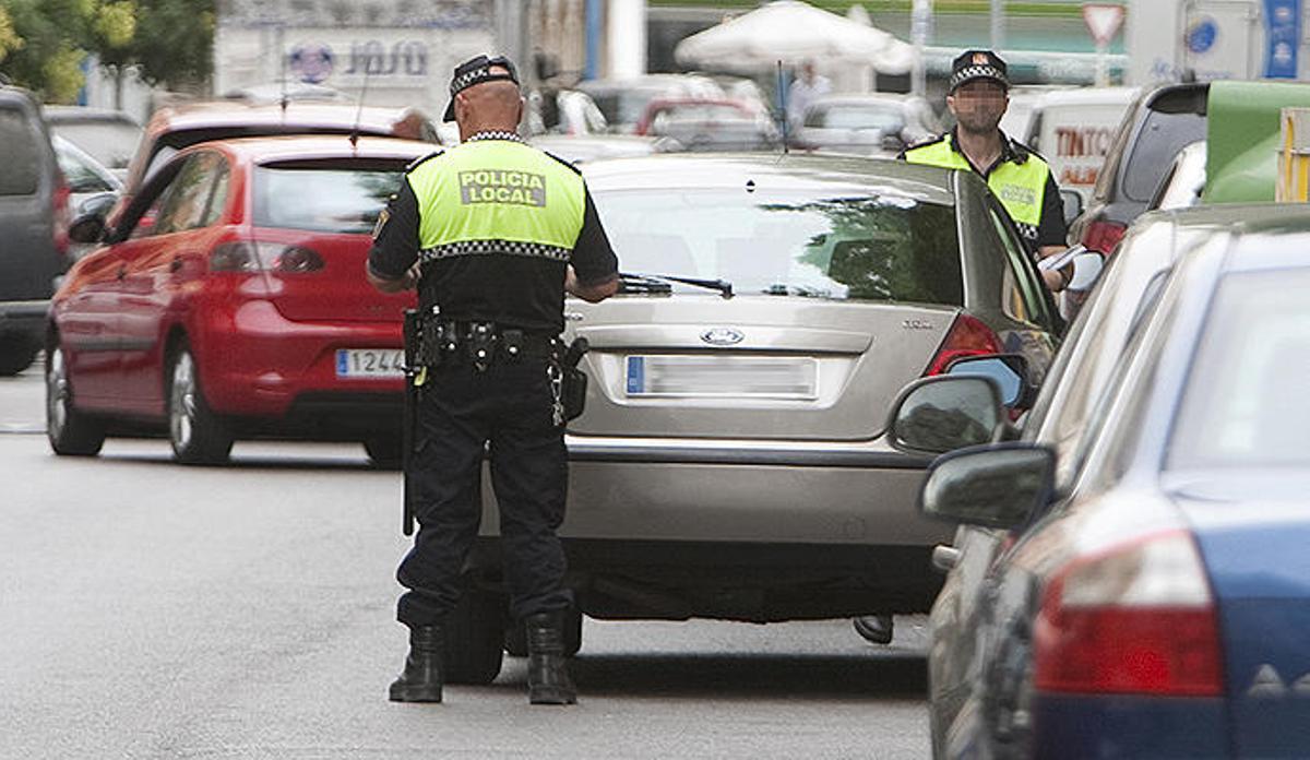 Dos agentes locales junto aun coche en doble fila.