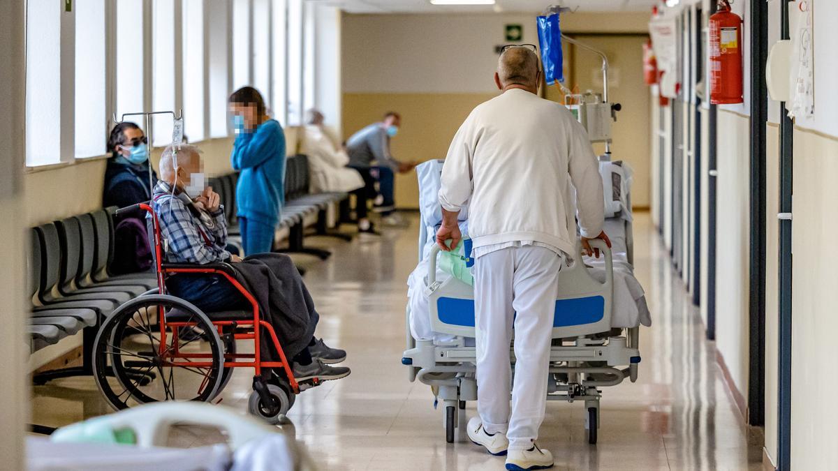 Un trabajador del Hospital traslada una camilla ante otros pacientes que esperan para ser atendidos, en una imagen reciente.