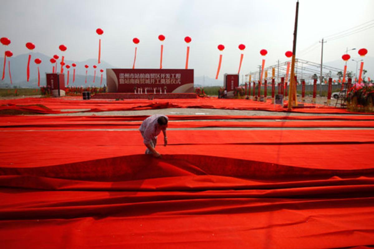 Un home col·loca una alfombra vermella durant la inauguració d’un edifici a Wenzhou, província de Zhejiang (Xina).