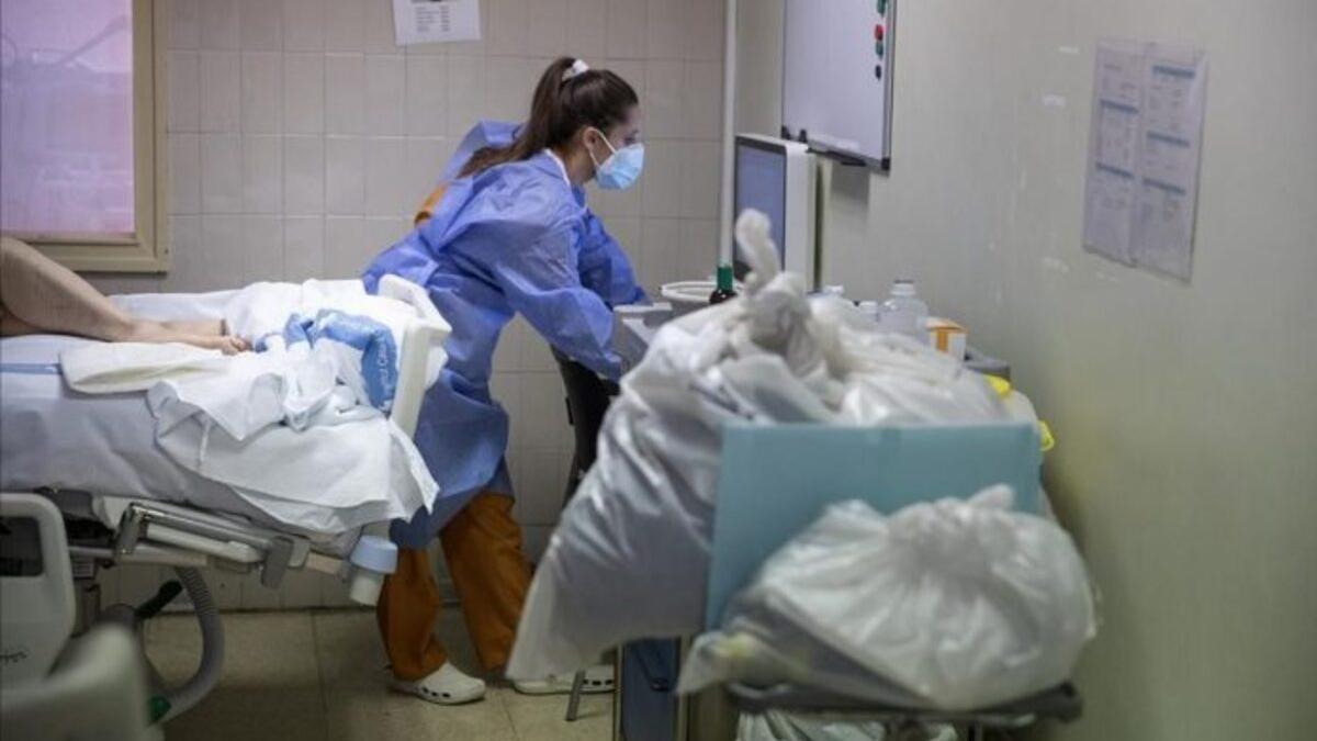 Una sanitaria con un enfermo de covid-19 en una habitación de hospital.