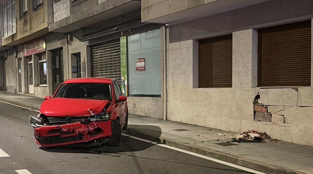 Uno de los vehículos implicados y el agujero que dejó en la pared de la vivienda.