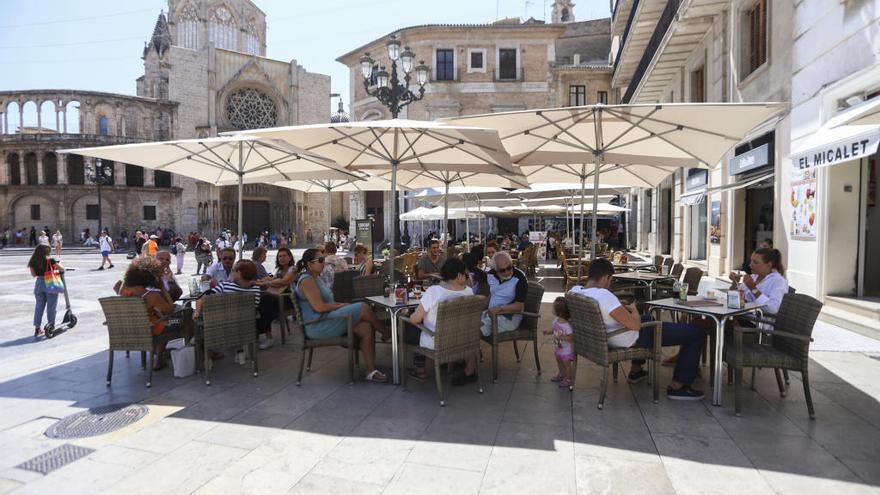 Turistas en una terraza, al resguardo del sol bajo unas sombrillas, ayer en València.
