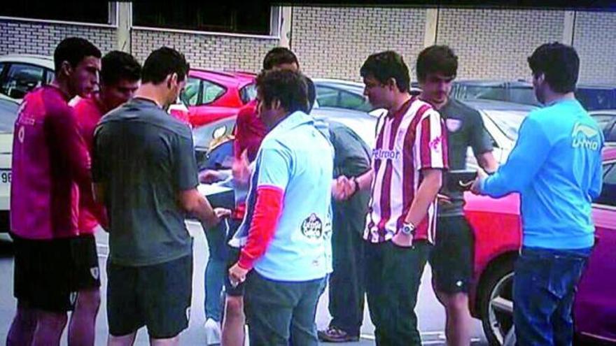 Arriba, miembros de la peña Zeru Urdin posan en Lezama con las cajas de mejillones llegados desde la Illa de Arousa gracias a la promesa de Carcamáns Celestes. Abajo, conversación entre los peñistas con algunos jugadores del Athletic como De Marcos, Aduriz y Gurpegi, durante la entrega de las cajas de moluscos enlatados que llegaron a Bilbao. // FDV