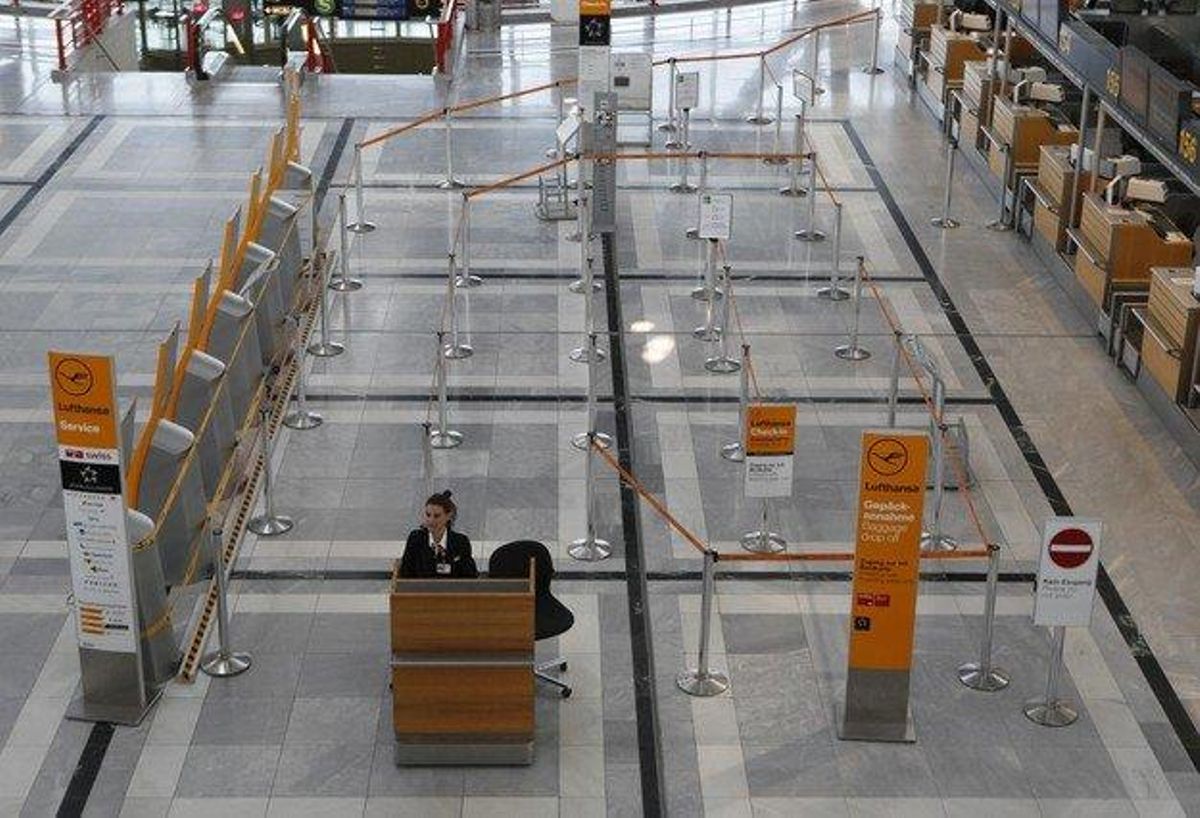A lonely employee of Germanys largest airline Lufthansa sits at an information counter at the Lufthansa check-in the terminal of the closed Stuttgart airport