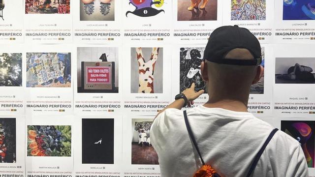 Un hombre contempla un panel de carteles de la exposición.