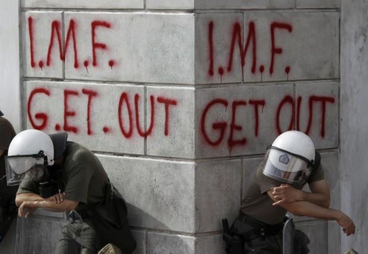 Greek riot policemen rest in front of grafit during violent demonstrations over austerity measures in Athens