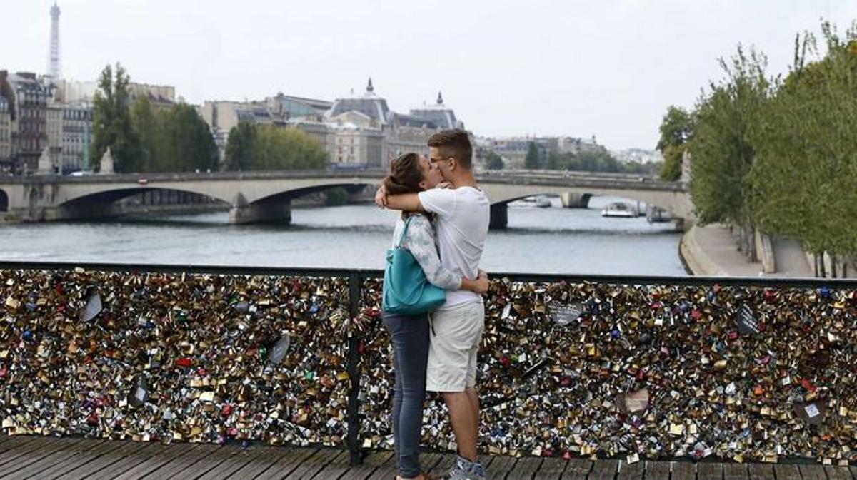 Una pareja se besa en el Pont des Arts de París ante los miles de 'candados del amor', hoy retirados, que amenazaban su estructura