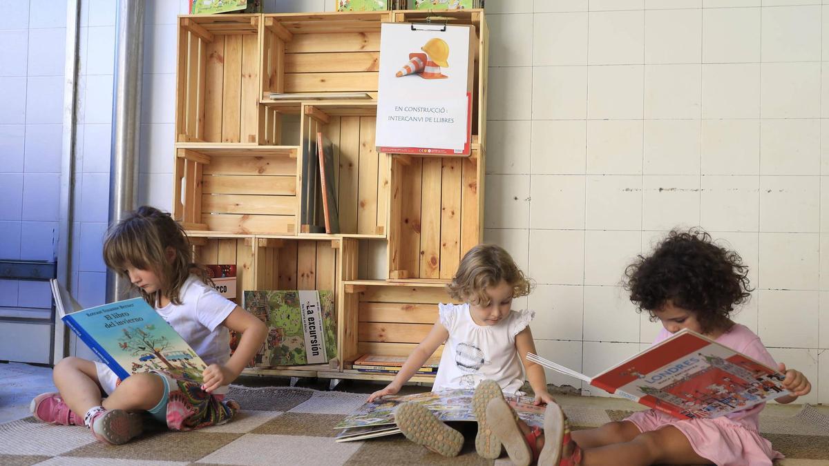 Niñas leyendo sentadas en el pasillo de una escuela de Barcelona.