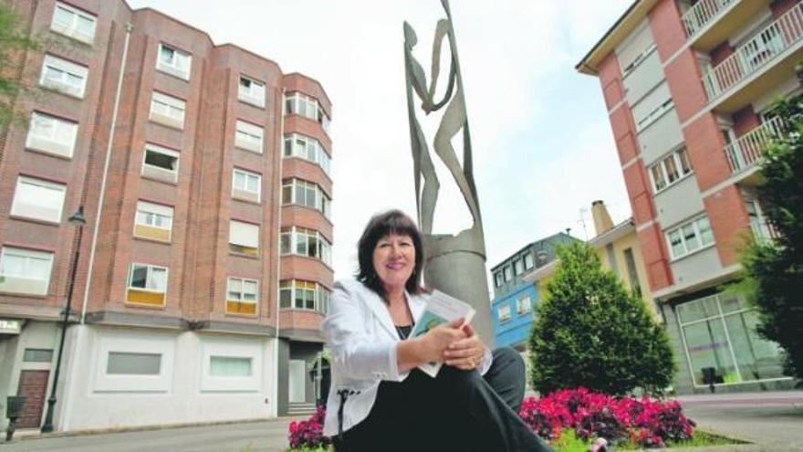 María Esther García, en la plaza de la Constitución de Piedras Blancas, ante la escultura «Tubo enamorado» y con su último libro en las manos.