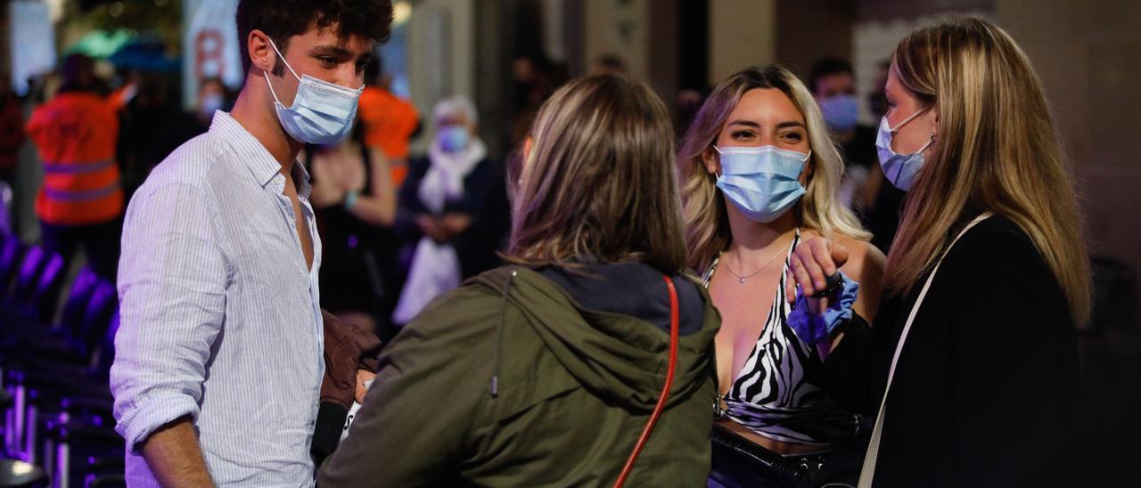 Algunas personas jóvenes en la calle con mascarilla.