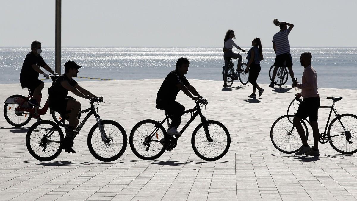 Gente con bicicletas en la playa de la Barceloneta.