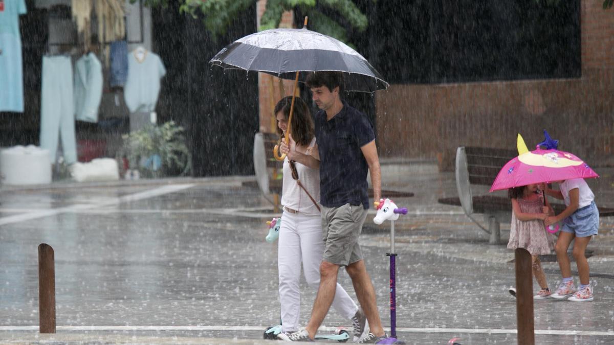 Una pareja se protege bajo el paraguas de la lluvia en Murcia.
