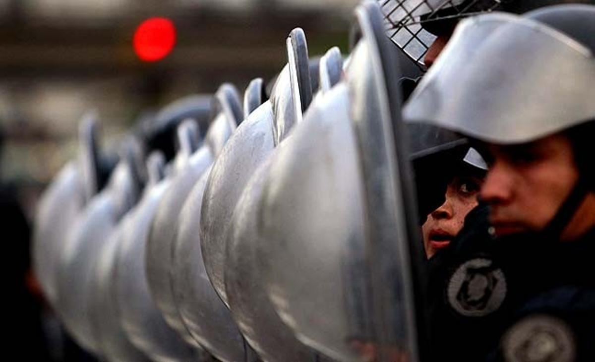 Una policia antiavalots s’escuda des de la seva posició durant els enfrontaments fora de l’estació de trens de Constitución a Buenos Aires (Argentina).