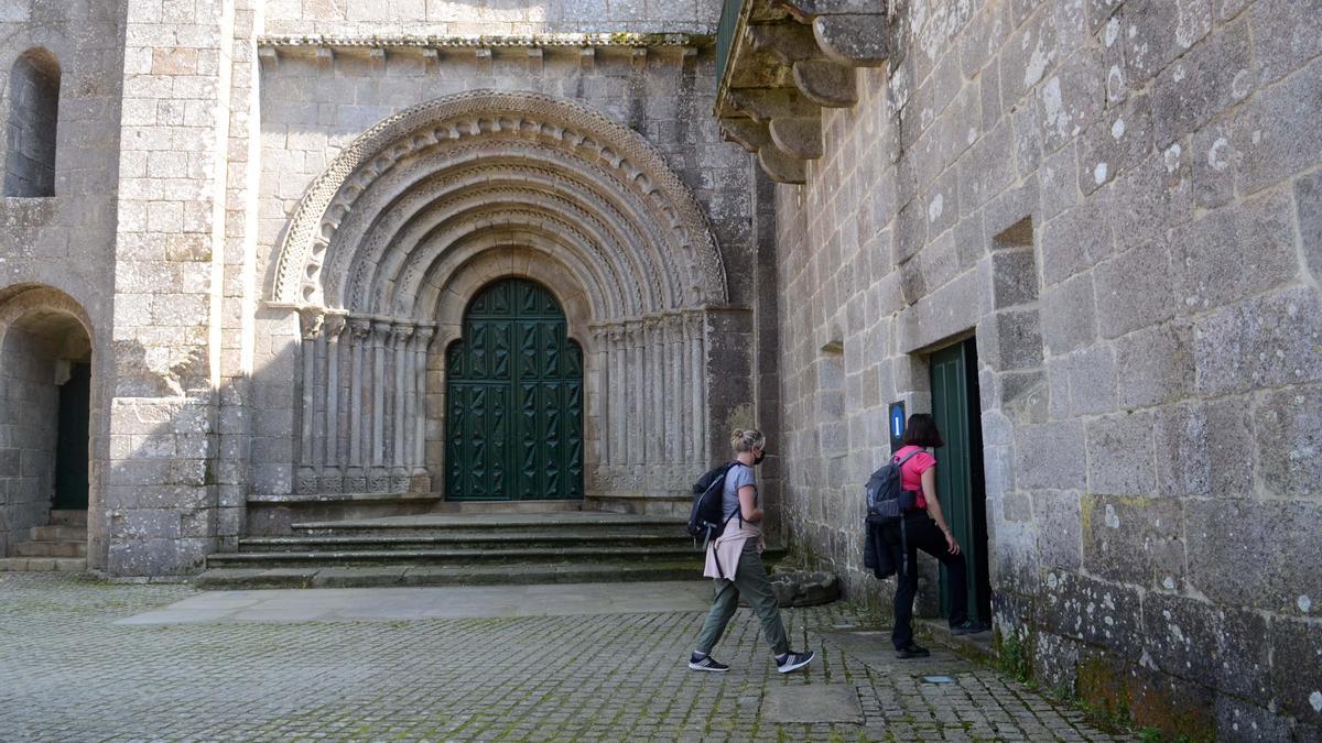 Dos mujeres acceden al claustro del monasterio de Armenteira, tras pasar por delante de la fachada de la iglesia