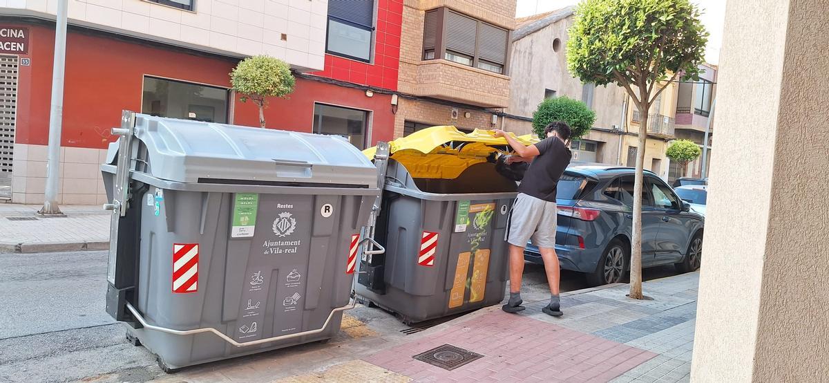 Un joven tira restos de basura en un contenedor en Vila-real, en una foto de archivo.