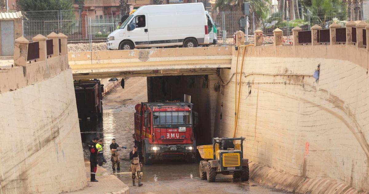 Arriba, los peatones atraviesan uno de los puentes de Paiporta sobre el barranco del Poyo que sigue en pie, aunque sin barandillas de seguridad. Abajo, paso inferior que cruza la línea de Cercanías en Benetússer, que será recuperado por la empresa pública Adif. Fotos de M. Á. Montesinos y Francisco Calabuig.