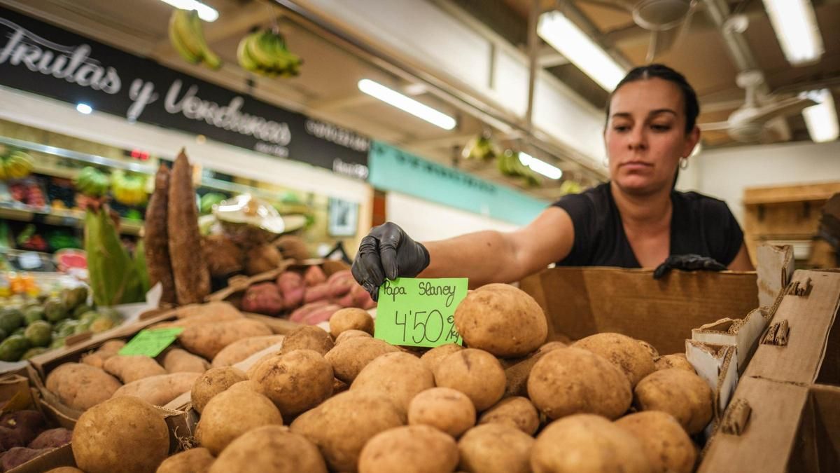 Una trabajadora coloca el cartel del precio de las papas en su puesto en el Mercado Nuestra Señora de África, en Santa Cruz.