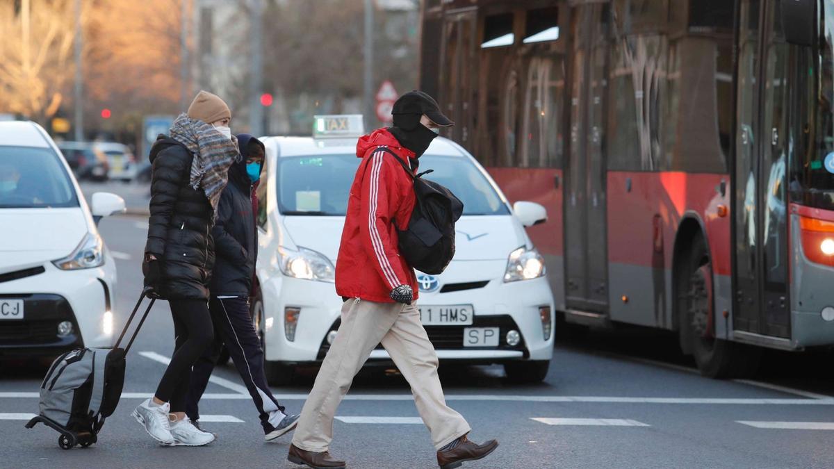 Un grupo de personas cruza un paso de peatones con mascarilla en València