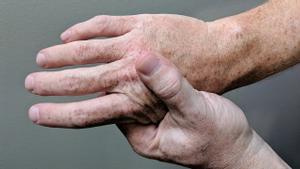 Persona masajeándose la mano debido al dolor.