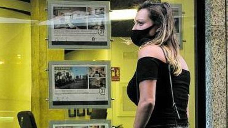 Una mujer ante las ofertas de casas en alquiler de una inmobiliaria.
