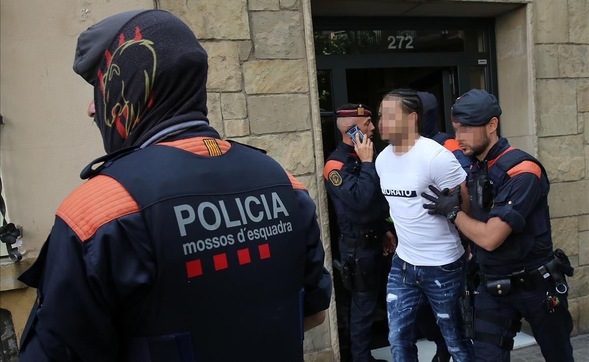 Operación policial en el barrio de Navas contra un grupo que distribuía cocaína a lateros de Barcelona. En la foto, unos agentes se llevan a un detenido.