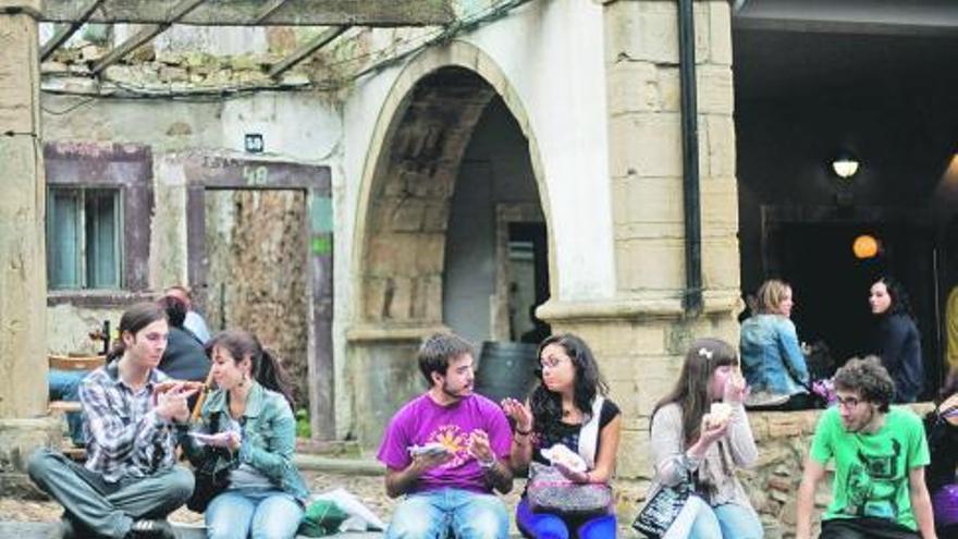 pulso ciudadano. Jóvenes comiendo sentados en un muro delante de un solar en ruinas del parque del Carbayedo. / ricardo solís