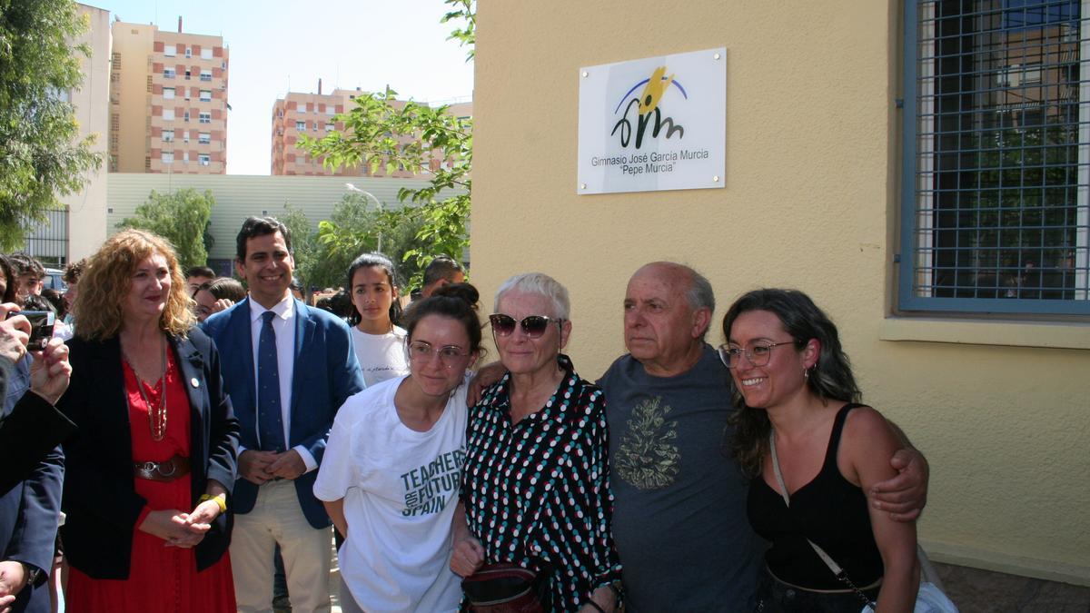 José García Murcia junto a su esposa y sus hijas posa delante de la placa con su nombre en la fachada del gimnasio.