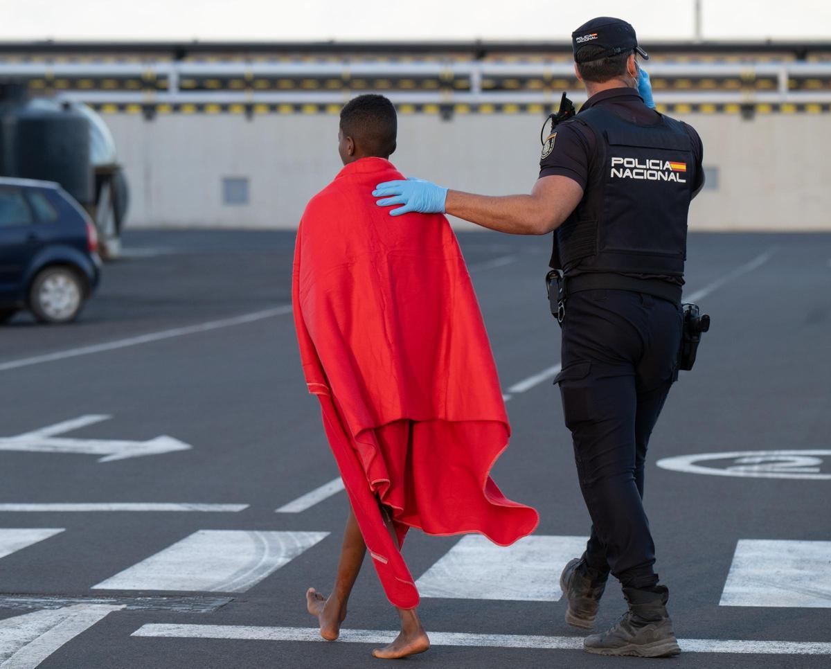 Un menor migrante recién llegado a Fuerteventura en 2025, acompañado de un Policía Nacional.