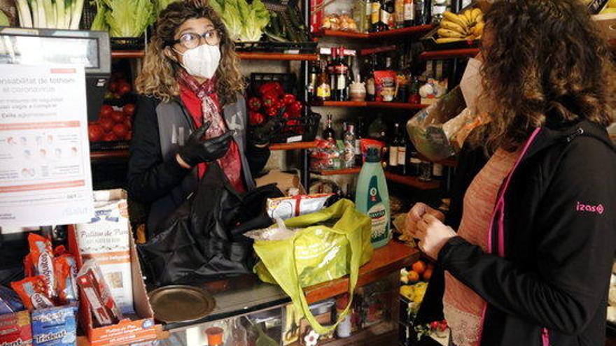 Una dependenta i una compradora amb mascareta per prevenir contagis de coronavirus en una botiga de Torrebesses