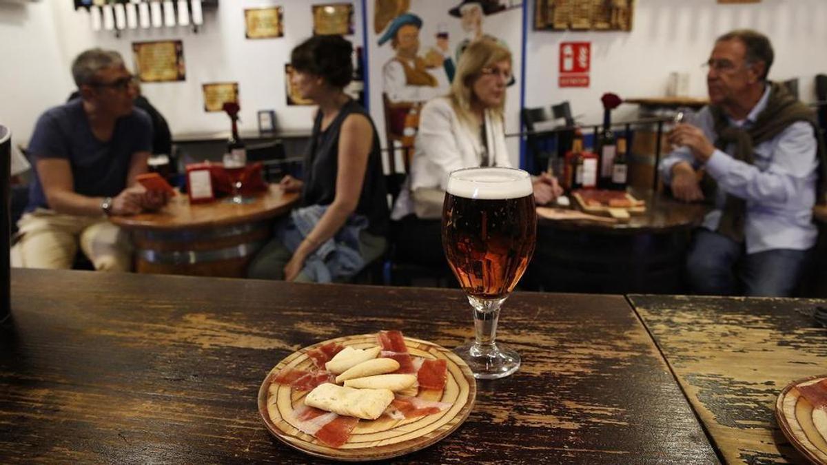 Ambiente de bar con una tapa y una caña servidas.