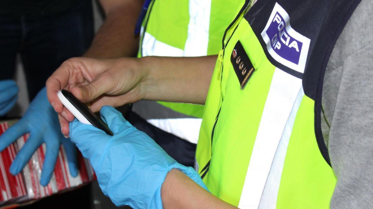 Un agente de Policía Nacional se incauta de un teléfono móvil.