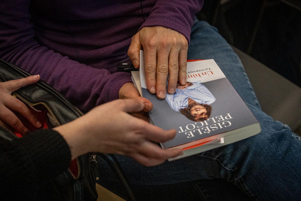 Unas asistentes al alcto sostienen uno de los libros