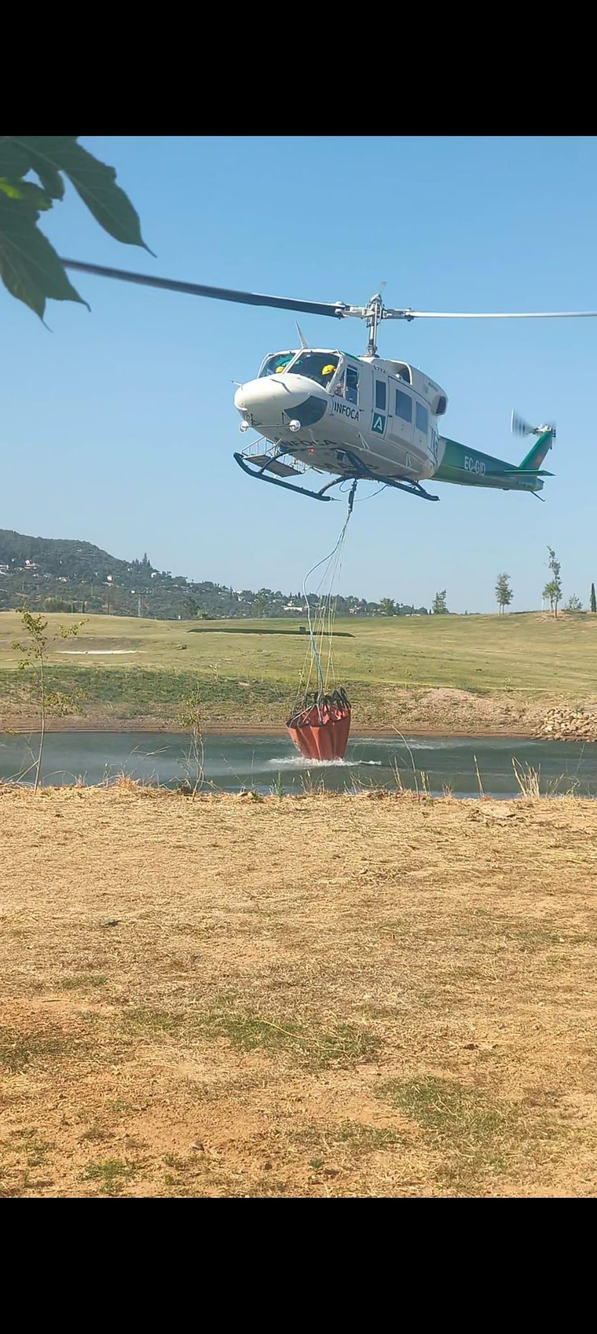 El helicóptero del Infoca carga agua para ayudar en las tareas de extinción del incendio de Las Golondrinas.