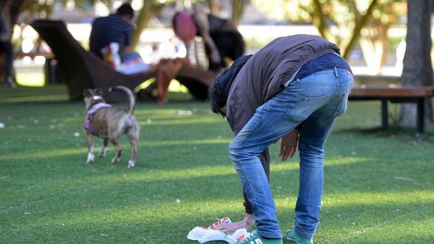 Un joven recoge los excrementos de su perro en un parque de Pontevedra. // Gustavo Santos