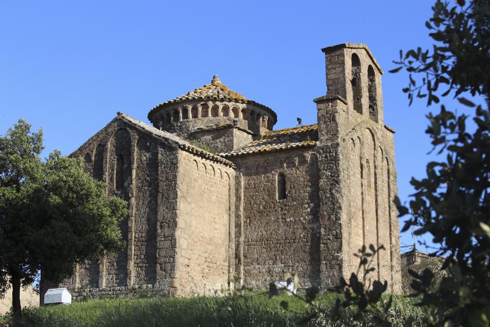 Sant Cugat del Racó. Rodejada d'alzines, el sol de la tarda il·lumina un monument romànic singular; sobre una planta de creu grega, amb dues naus creuades, s'alça un cimbori circular, únic a Catalunya