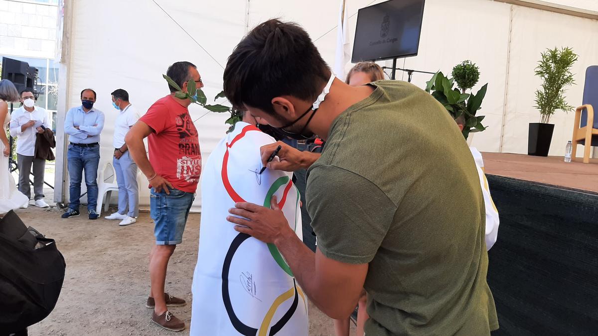 Rodrigo Germade firma sobre la bandera olímpica de una vecina.