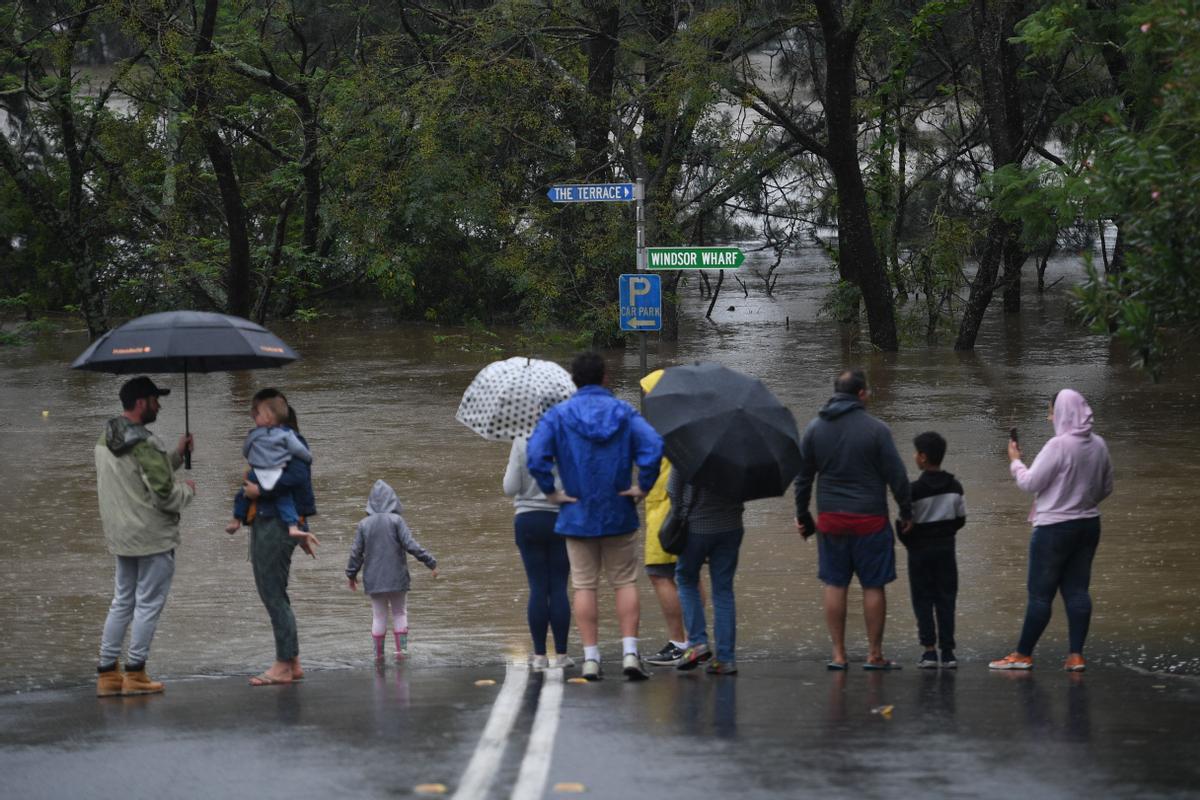 Curiosos ante el puente de Windsor, anegado por las inundaciones en Australia