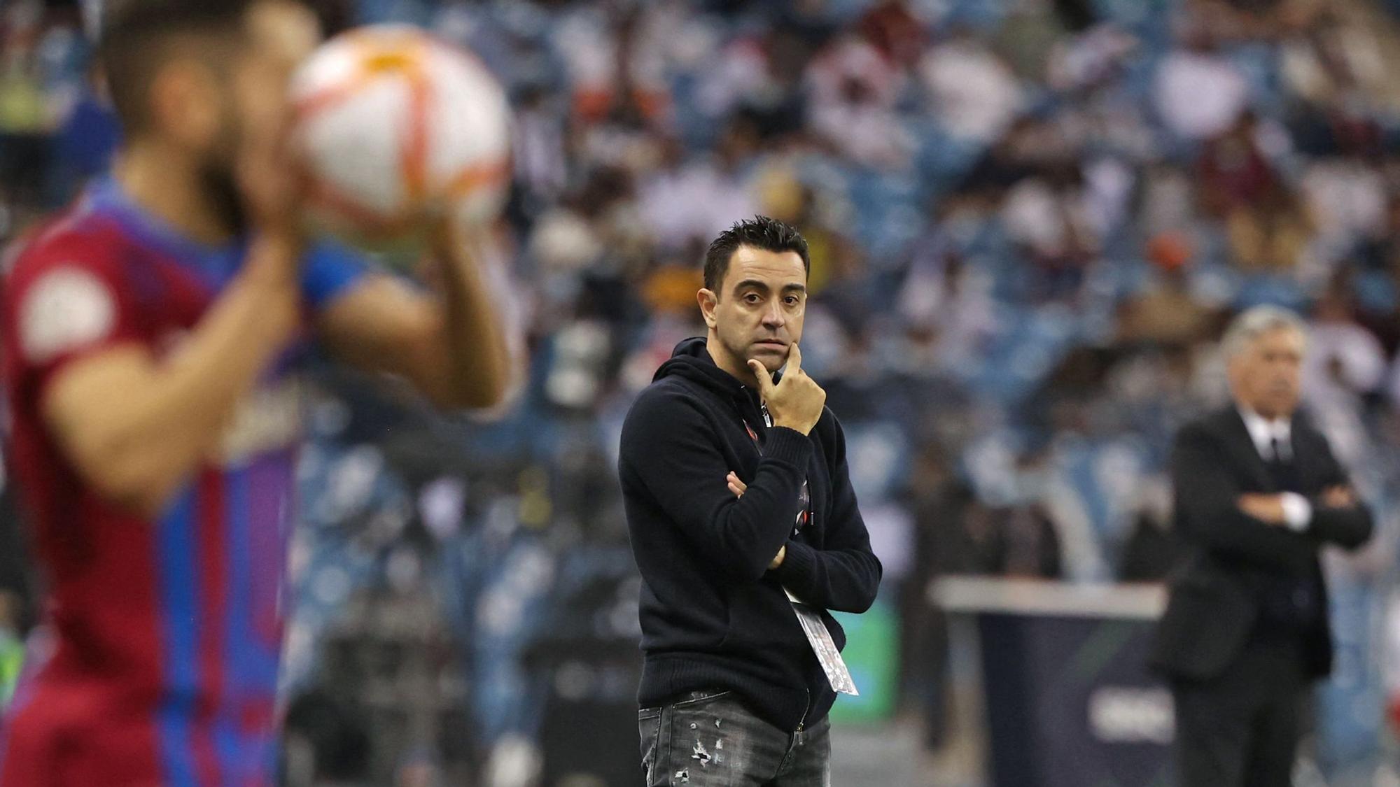 Barcelona's Spanish coach Xavi (C) watches from the sidelines during the Spanish Super Cup semi-final football match between Barcelona and Real Madrid at the King Fahad International stadium in the Saudi capital Riyadh on January 12, 2022. (Photo by Fayez Nureldine / AFP)