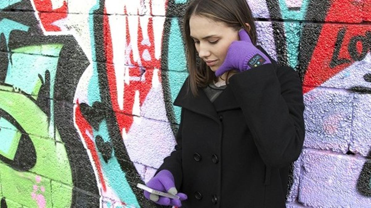 Una mujer conversa telefónicamente a través de los guantes hi-Call y su móvil.