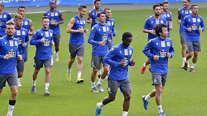 Los futbolistas del Deportivo calientan durante la sesión de ayer en Riazor.