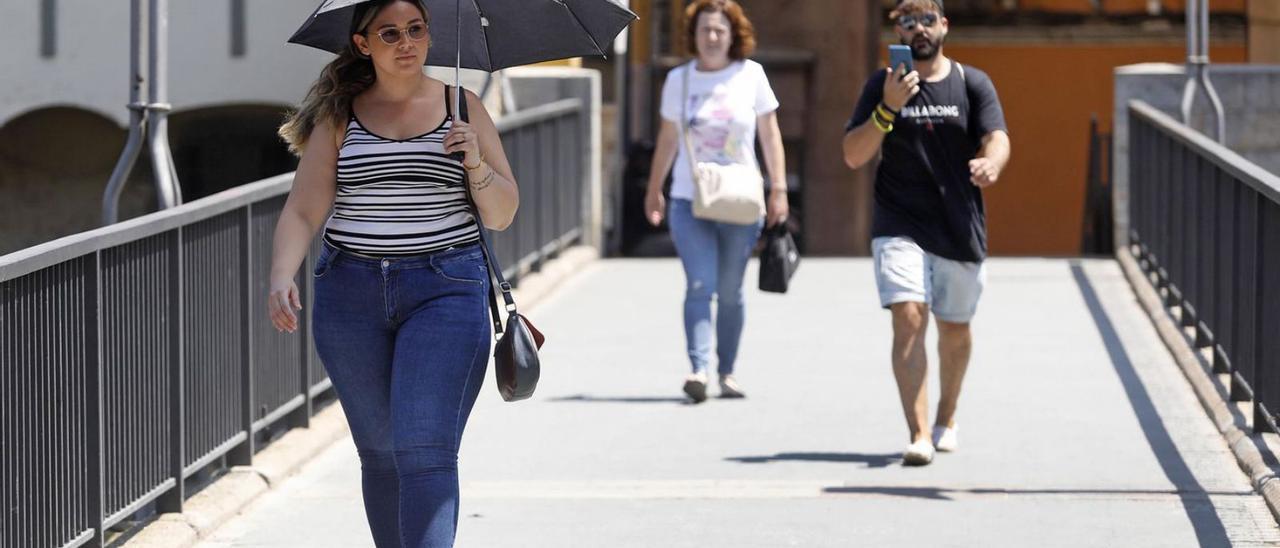 Una noia es protegeix de la calor amb un paraigua, aquest estiu, a Girona.  | ANIOL RESCLOSA