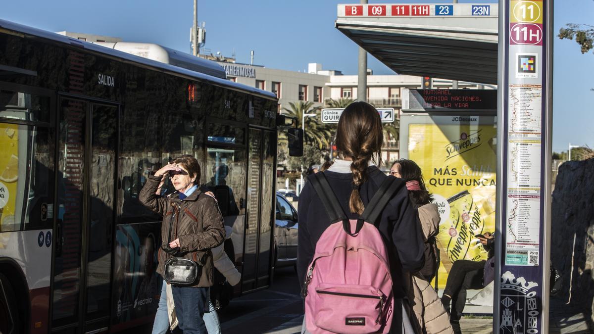 Una estudiante espera en una parada de autobús de Alicante.