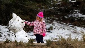 Una niña, con un muñeco de nieve en la localidad alicantina de Alcoy, este viernes.