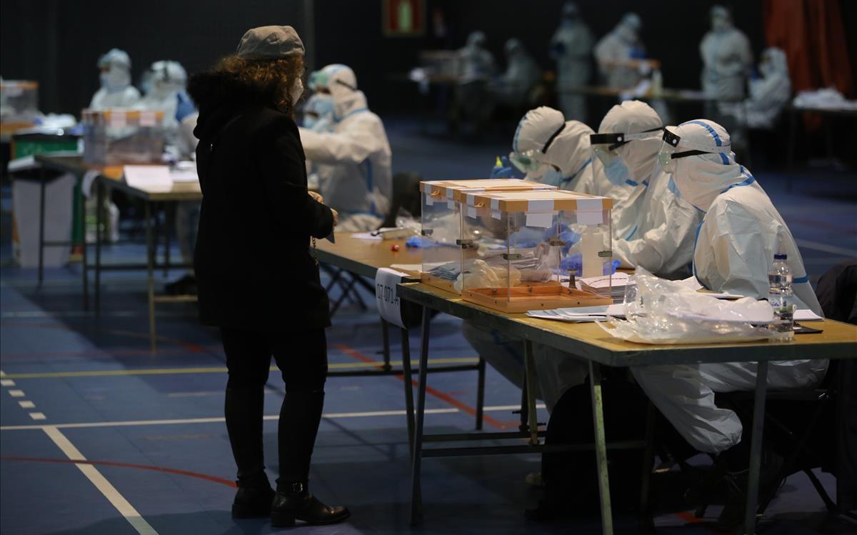 Votación de gente en cuarentena por Covid , la gente de las mesas con trajes epis en el Polideportivo de El Carmel.